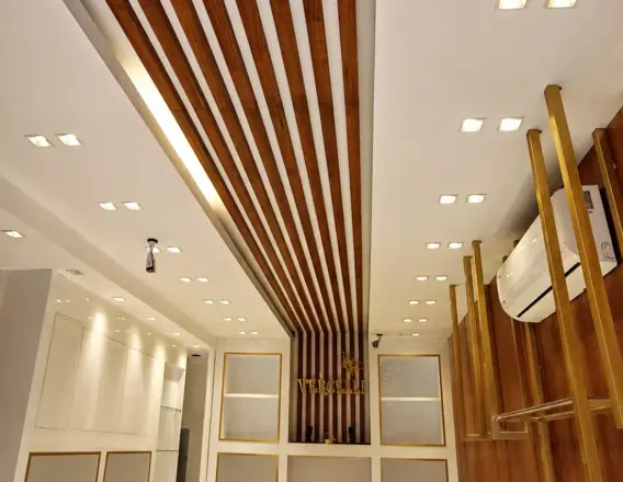 Murano-fitted retail showroom — wood-slat ceiling and gold-trim reception, a high-end fit-out result